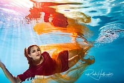 Underwater Portrait of female model in red dress - synchronized studio light shining into pool - ikelite - nikon